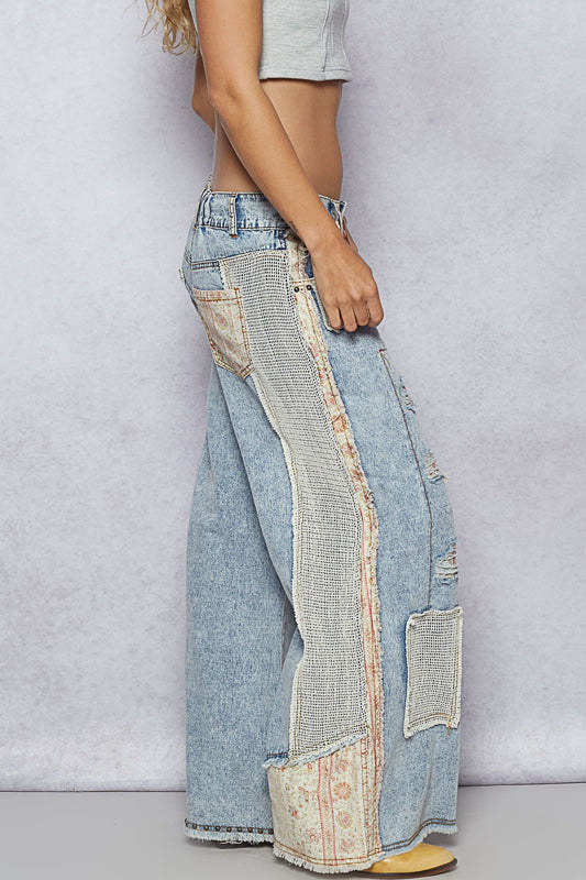 Light blue patchwork jeans worn by a person on a plain background