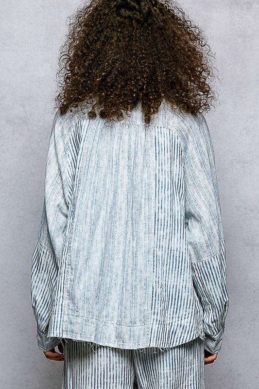 Person wearing a light blue striped shirt and pants against a gray background