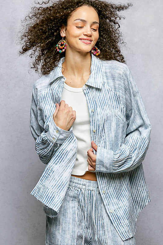 Woman wearing a light blue striped shirt and pants against a gray background