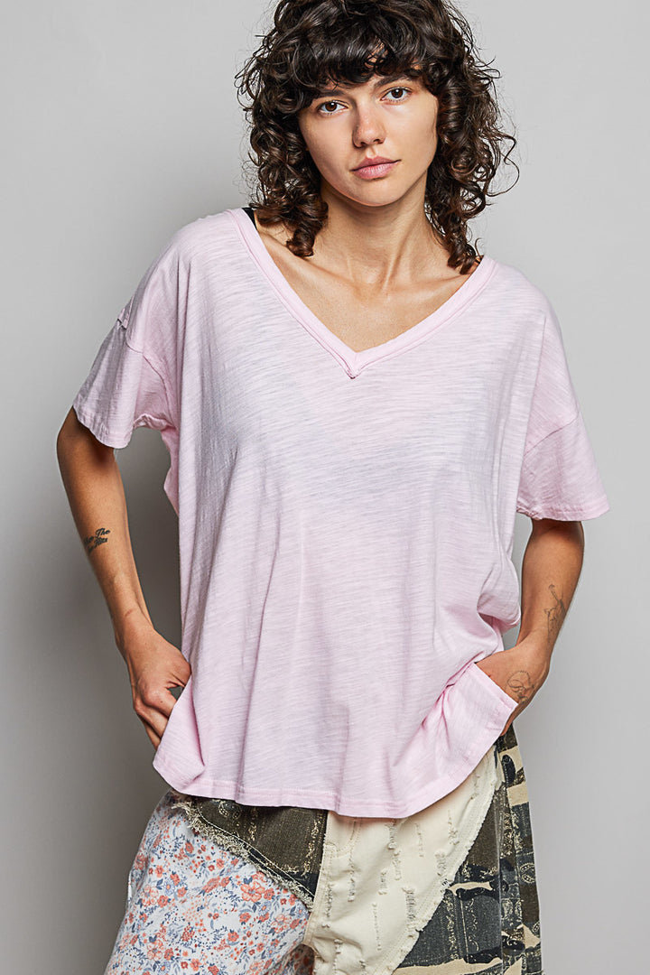 Woman wearing a light pink oversized t-shirt against a gray background