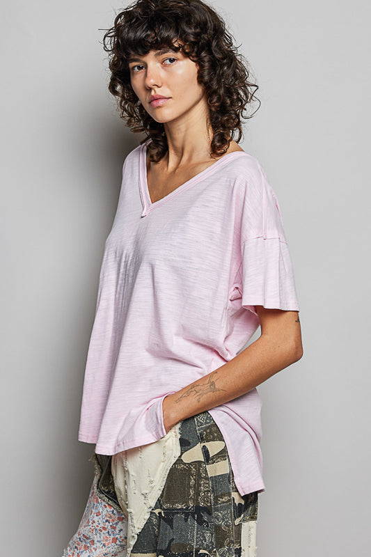 Woman wearing a light pink oversized shirt against a plain background