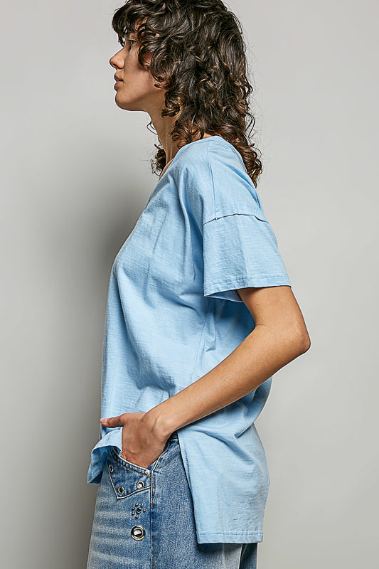 Person wearing a light blue oversized shirt and jeans against a plain background