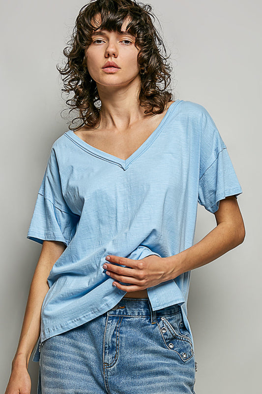 Woman wearing a light blue t-shirt and jeans against a plain background