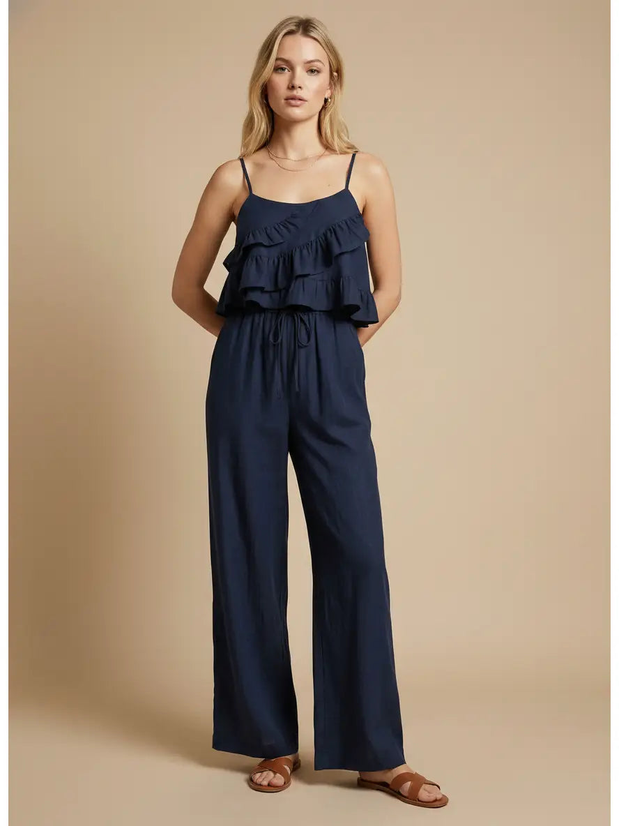 Woman wearing a navy blue jumpsuit with ruffled top on a beige background