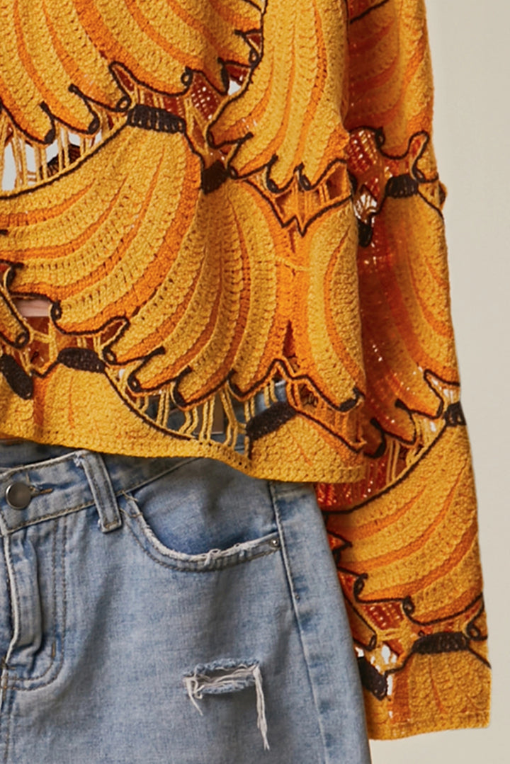 Close-up of a person wearing a bright yellow patterned top and blue jeans.