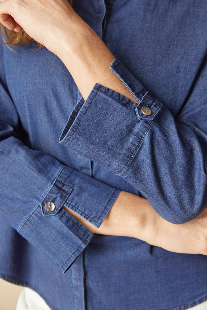 Close-up of a person wearing a blue denim shirt with rolled-up sleeves.