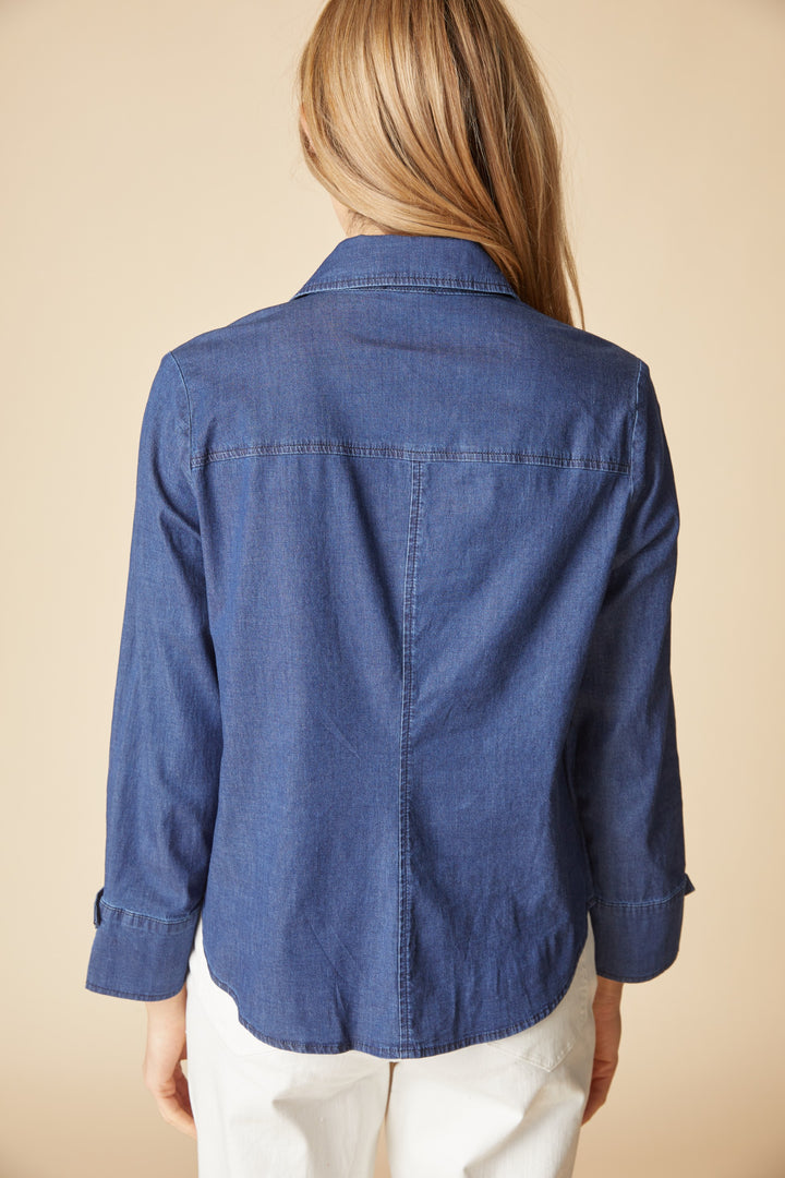 Person wearing a blue denim shirt against a beige background