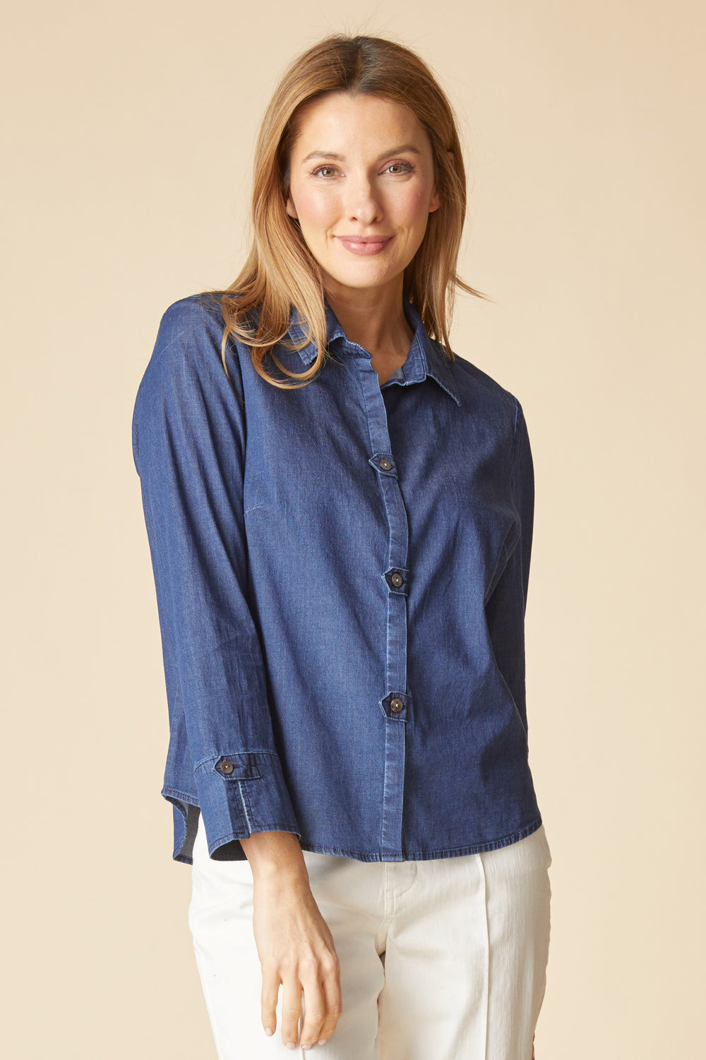 Woman wearing a blue denim shirt against a beige background