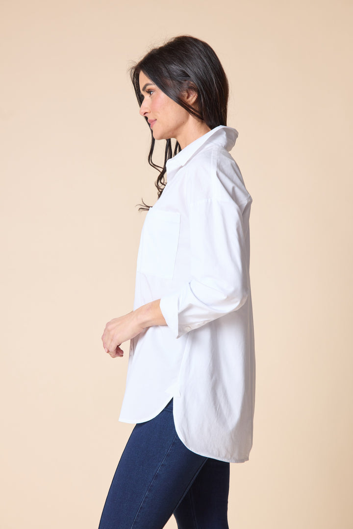 Woman wearing a white shirt and blue jeans against a beige background