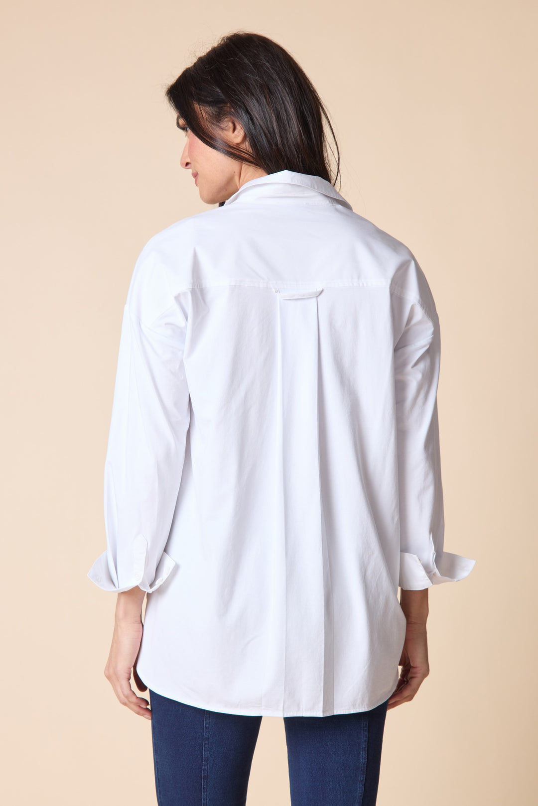 Woman wearing a white shirt with rolled-up sleeves on a beige background