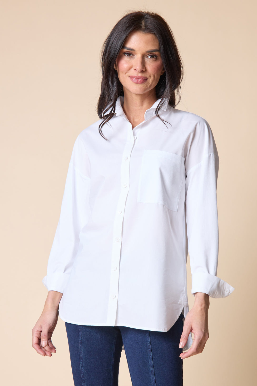 Woman wearing a white shirt and blue jeans against a beige background