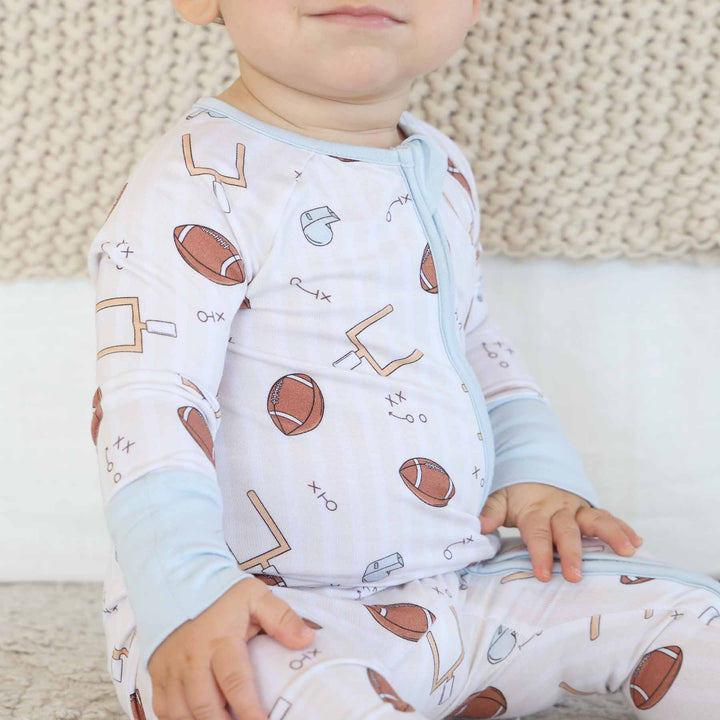 Child wearing a onesie with sports-themed design on a textured surface