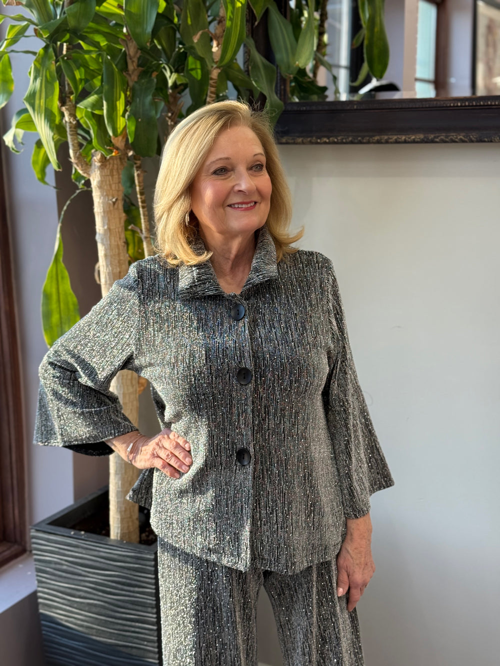 Shimmering silver jacket with large black buttons and 3/4-length sleeves, paired with matching silver pants.