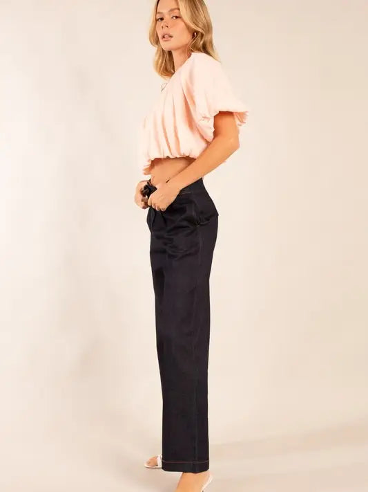 Woman wearing a pink top and black pants on a beige background