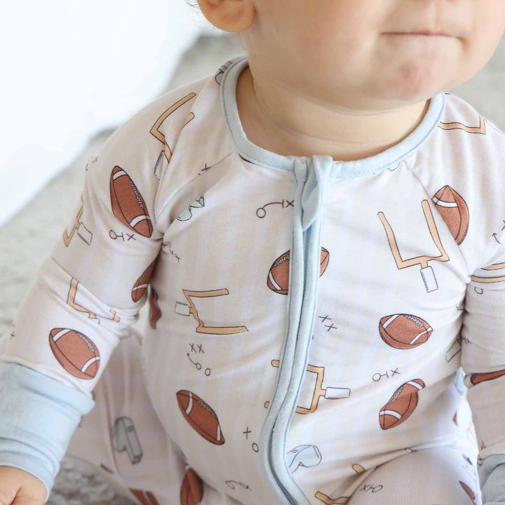 Baby wearing a onesie with football and sports pattern