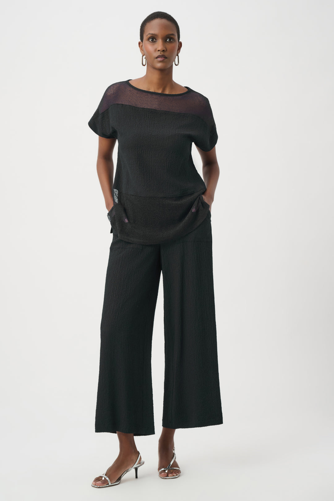 Woman wearing a black outfit with wide-leg pants on a white background