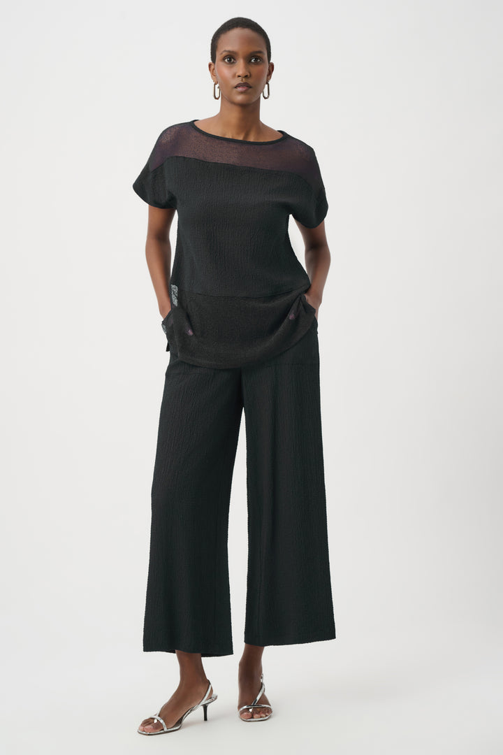 Woman wearing a black outfit with wide-leg pants on a white background