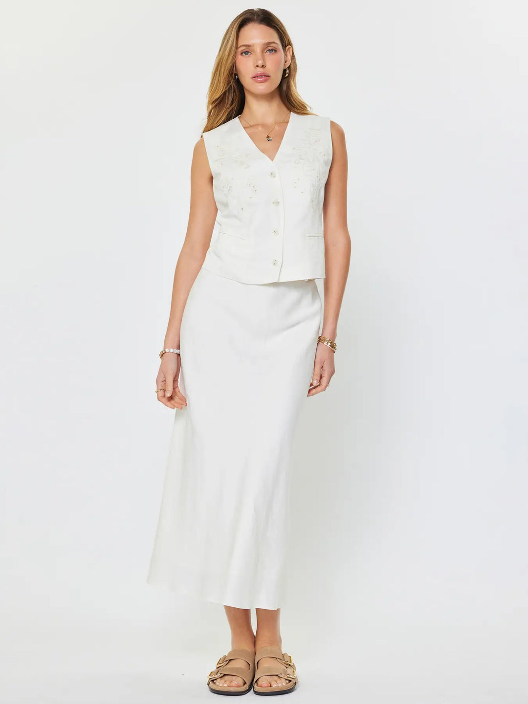 Woman wearing a white sleeveless top and skirt set on a plain background