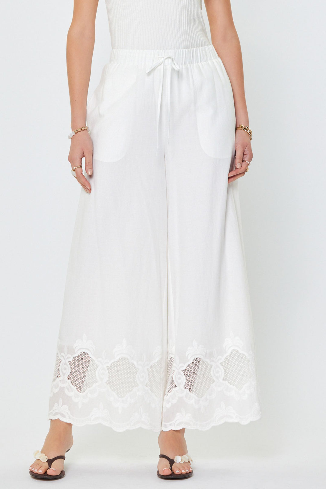 White lace-trimmed pants worn by a person on a white background