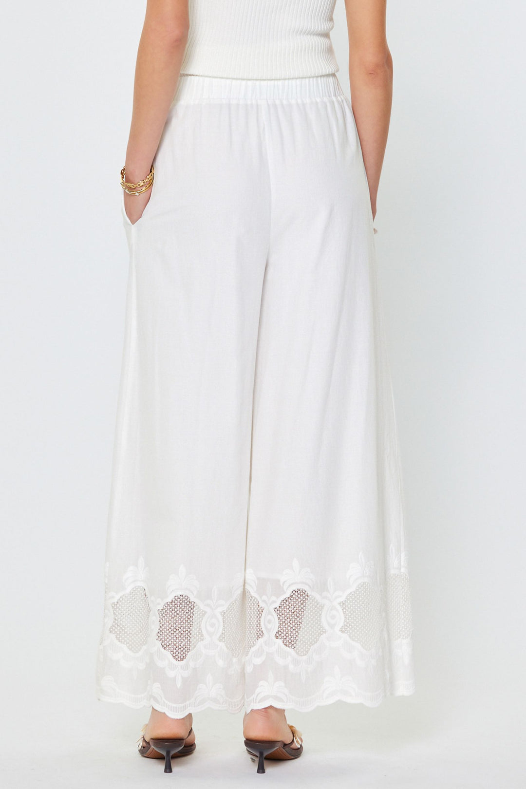 White pants with floral cut-out details on a white background