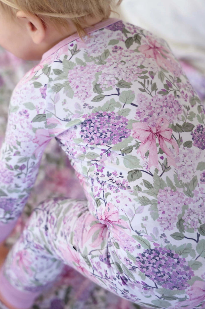 Child wearing a floral outfit with pink and purple flowers.