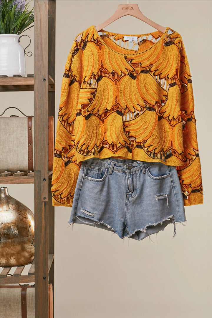 Yellow banana-patterned shirt and denim shorts on a hanger against a neutral background