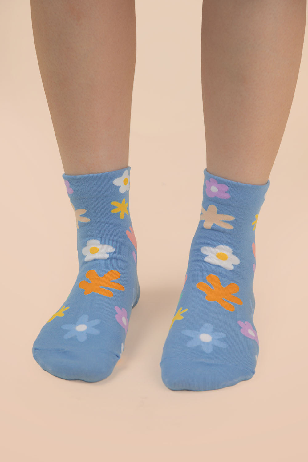Blue socks with colorful floral patterns worn by a person on a beige background