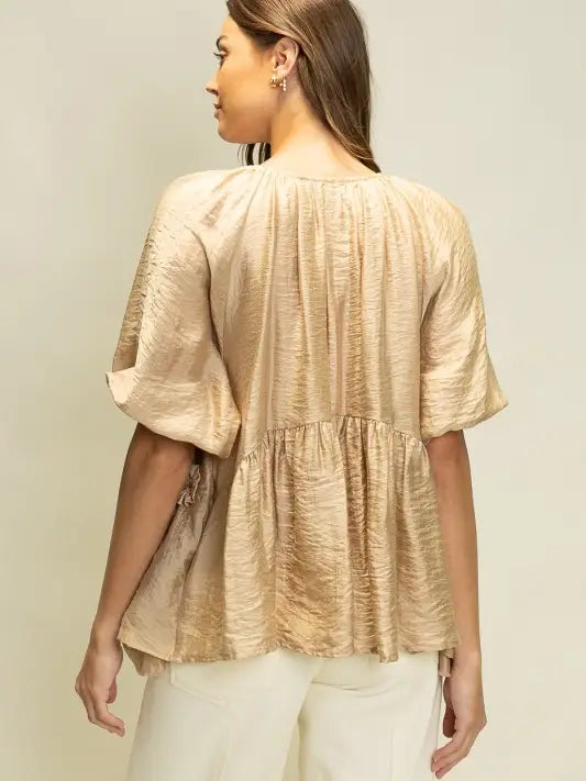 Woman wearing a beige textured blouse against a plain background