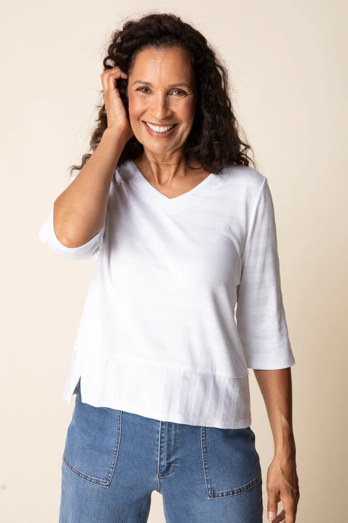 Woman wearing a white shirt and blue jeans against a beige background