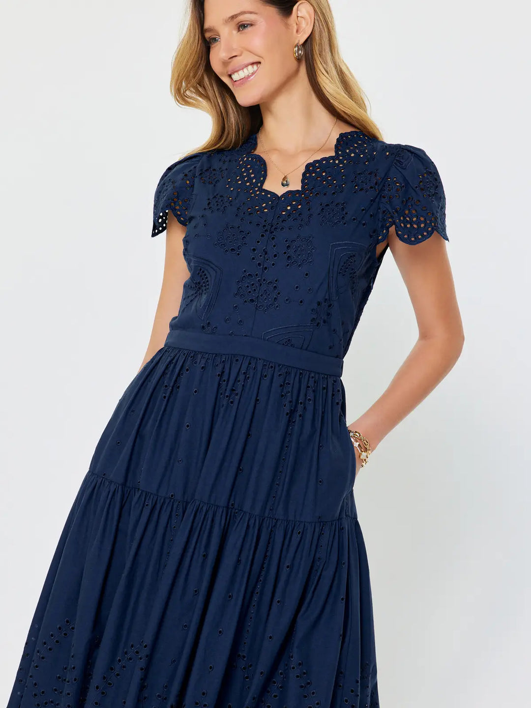 Woman wearing a navy blue dress with lace details on a white background