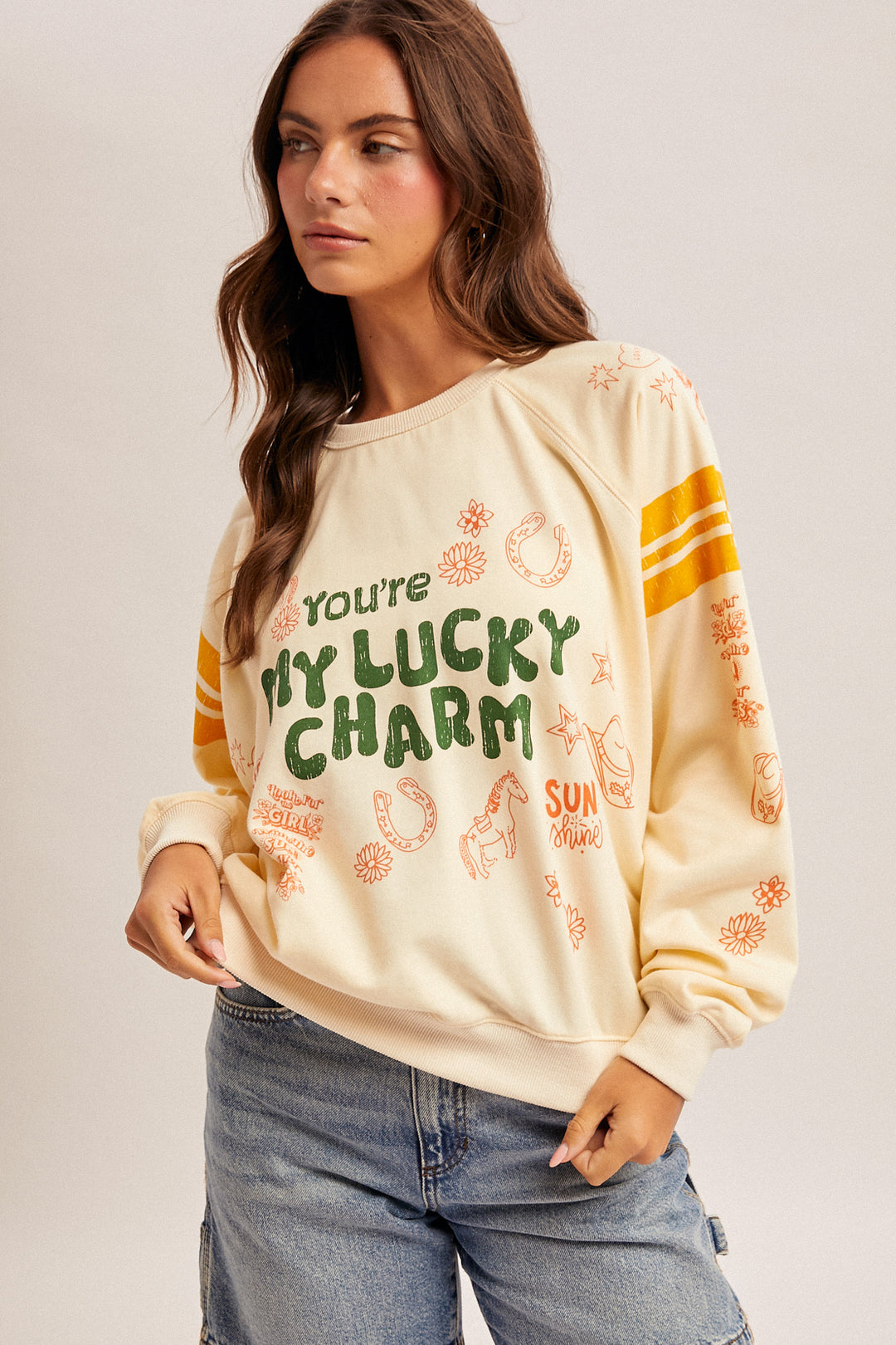 Woman wearing a cream sweatshirt with text and patterns on a plain background