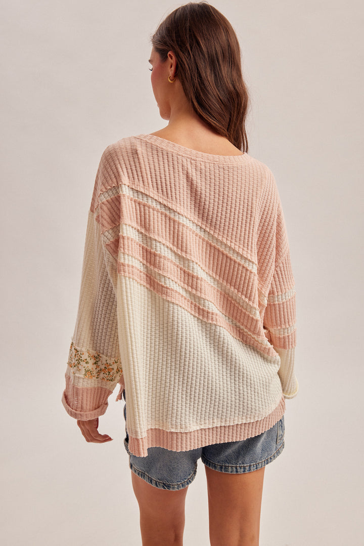 Woman wearing a patterned top and denim shorts on a plain background