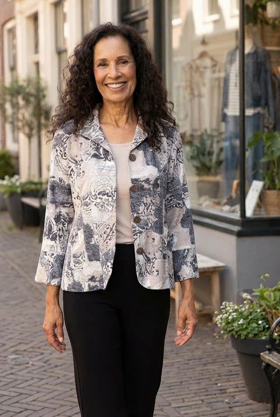 Woman wearing a patterned jacket standing on a street with shops in the background