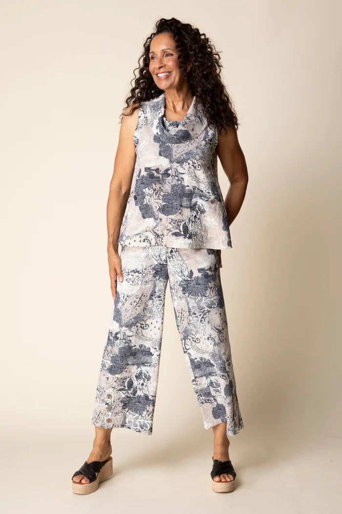 Woman wearing a floral sleeveless top and pants against a beige background