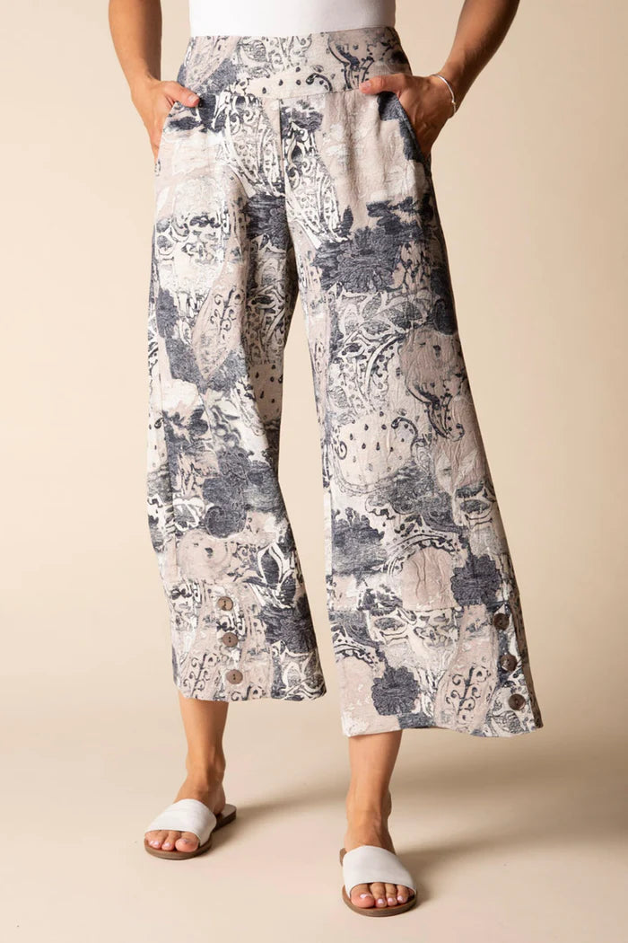 Person wearing floral-patterned wide-leg pants on a beige background