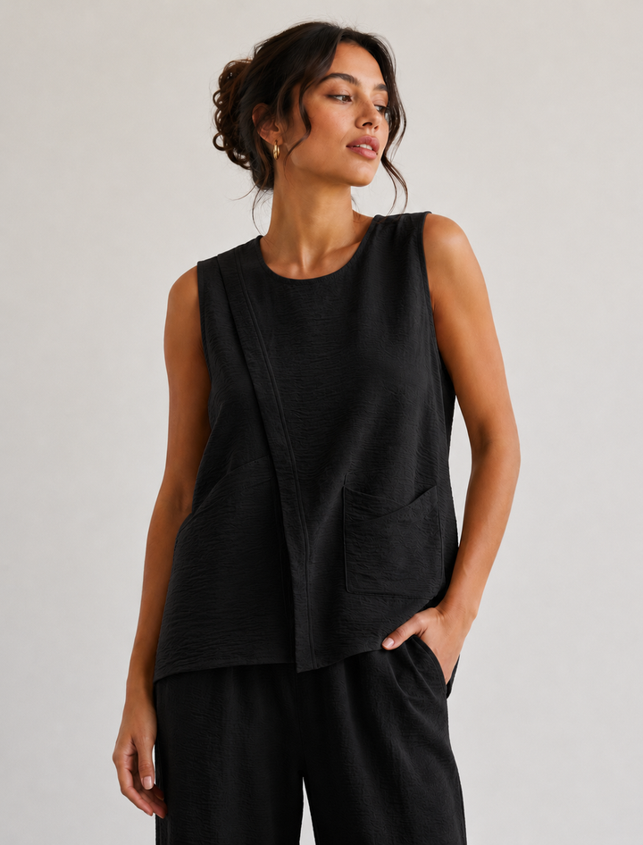 Woman wearing a black sleeveless top and pants against a plain background