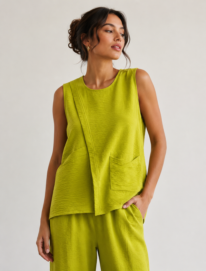 Woman wearing a green sleeveless top and pants against a plain background