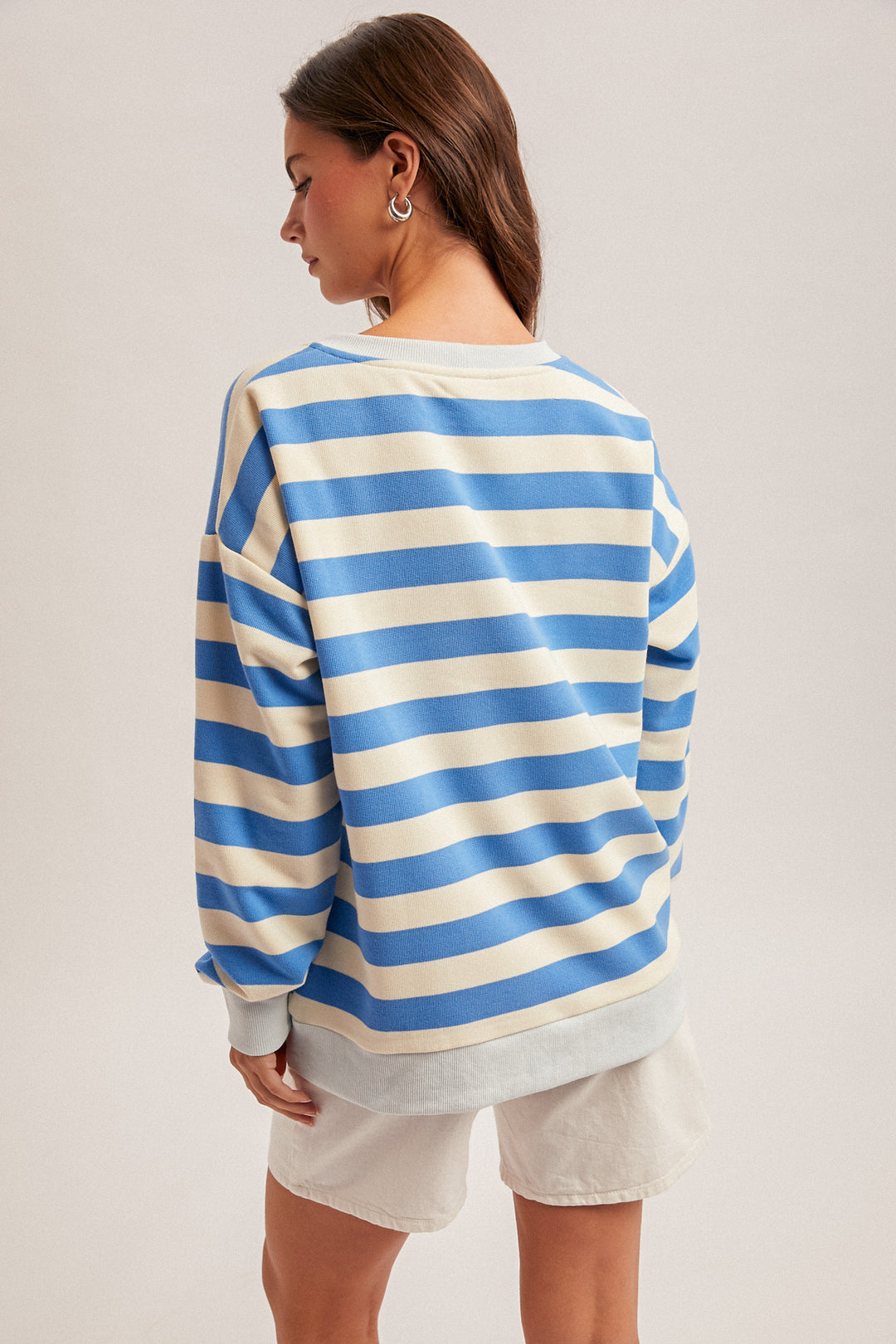 Person wearing a blue and white striped sweater on a plain background