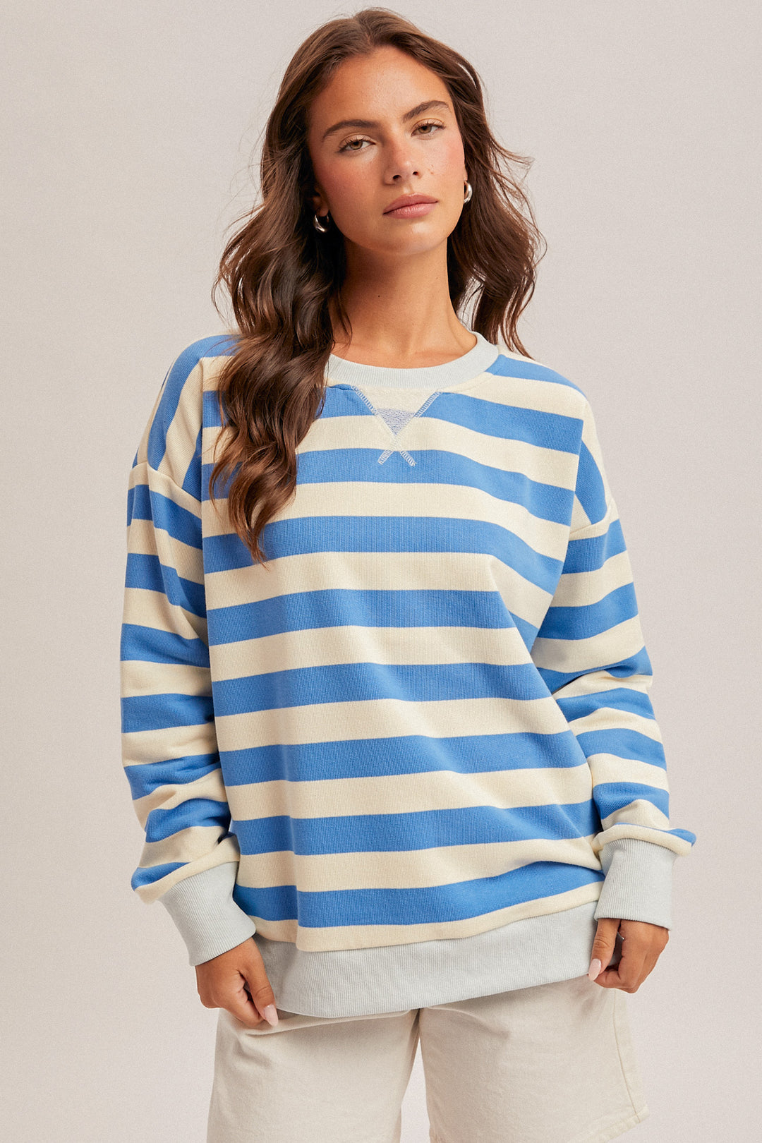 Woman wearing a blue and white striped sweater against a plain background