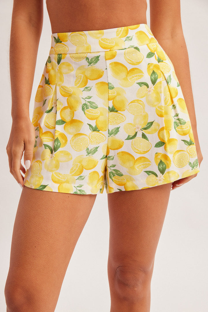 Person wearing a yellow lemon print skirt on a plain background