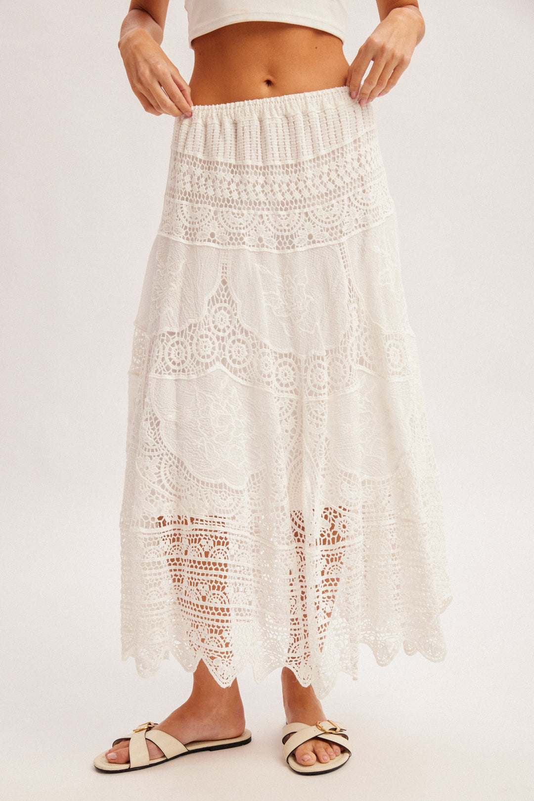 White lace skirt worn by a person on a light pink background