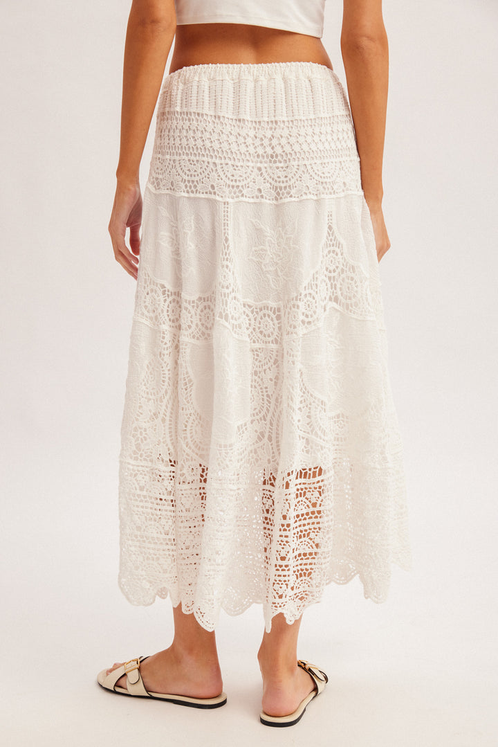 White lace skirt worn by a person on a plain background