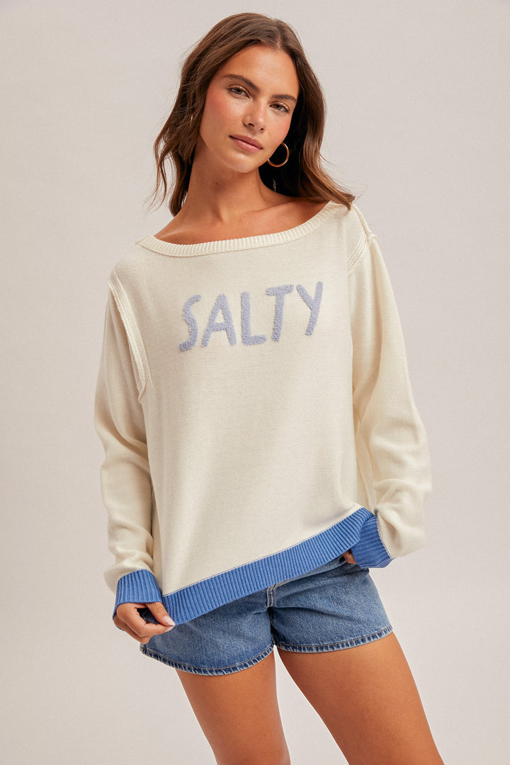 Woman wearing a cream sweater with &