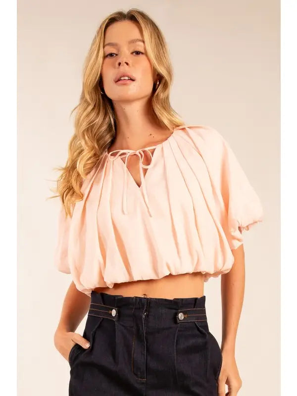 Woman wearing a light pink blouse with a plain background