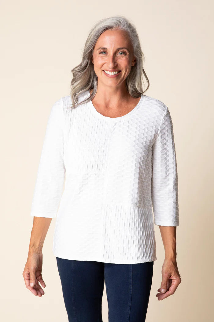 Woman wearing a white textured sweater against a beige background