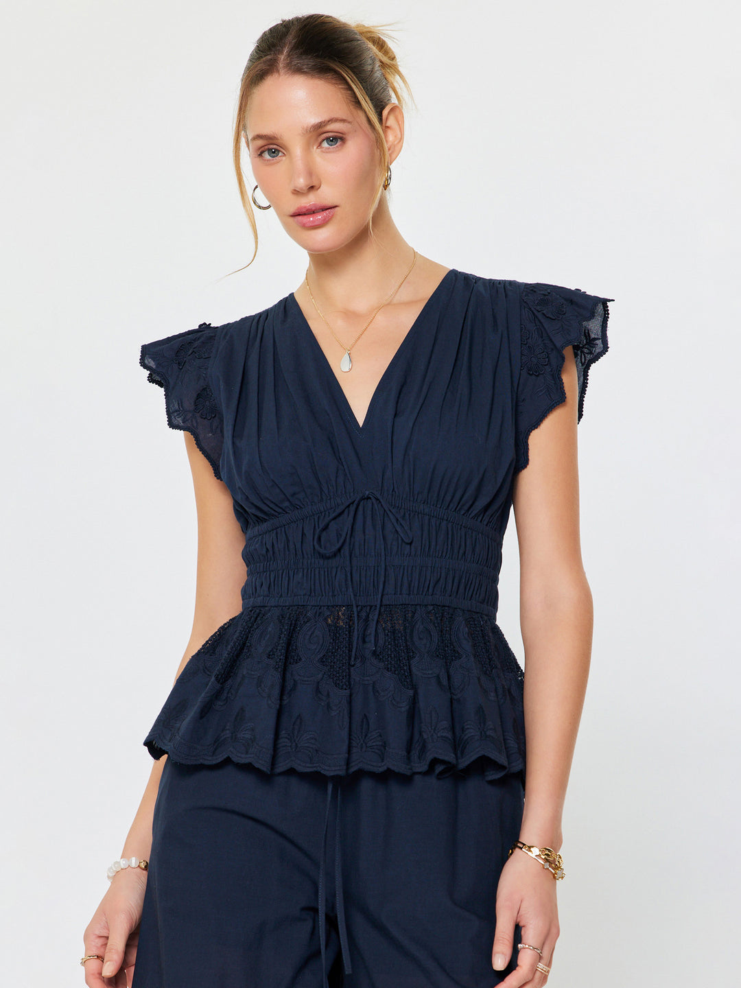Woman wearing a navy blue peplum top against a white background
