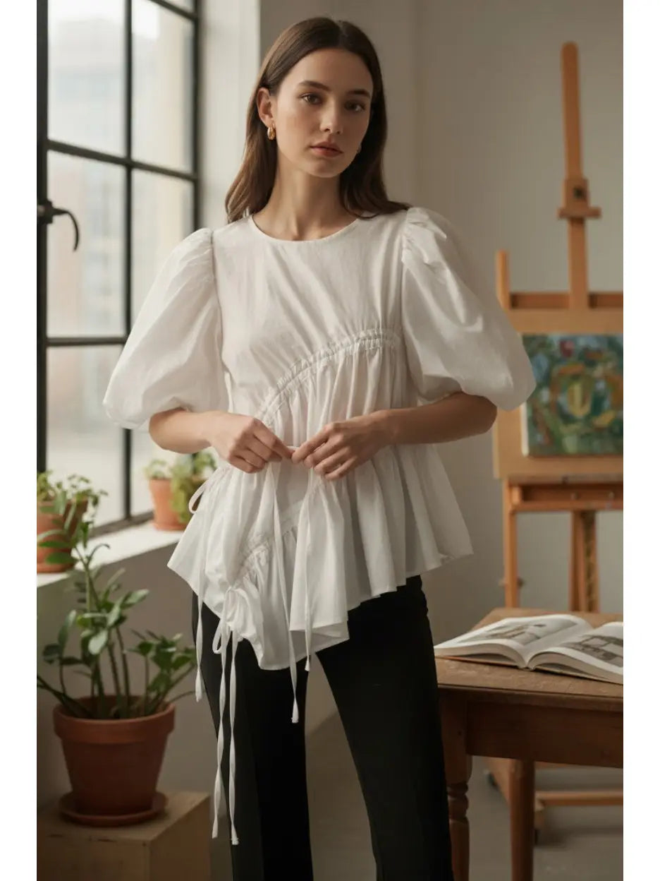 Woman wearing a white blouse in a room with plants and a painting.