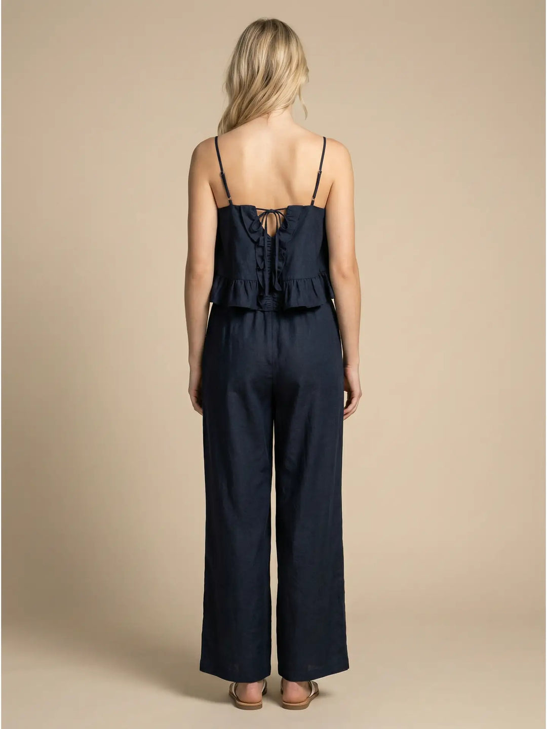 Woman wearing a navy blue jumpsuit against a beige background