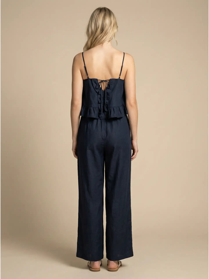 Woman wearing a navy blue jumpsuit against a beige background