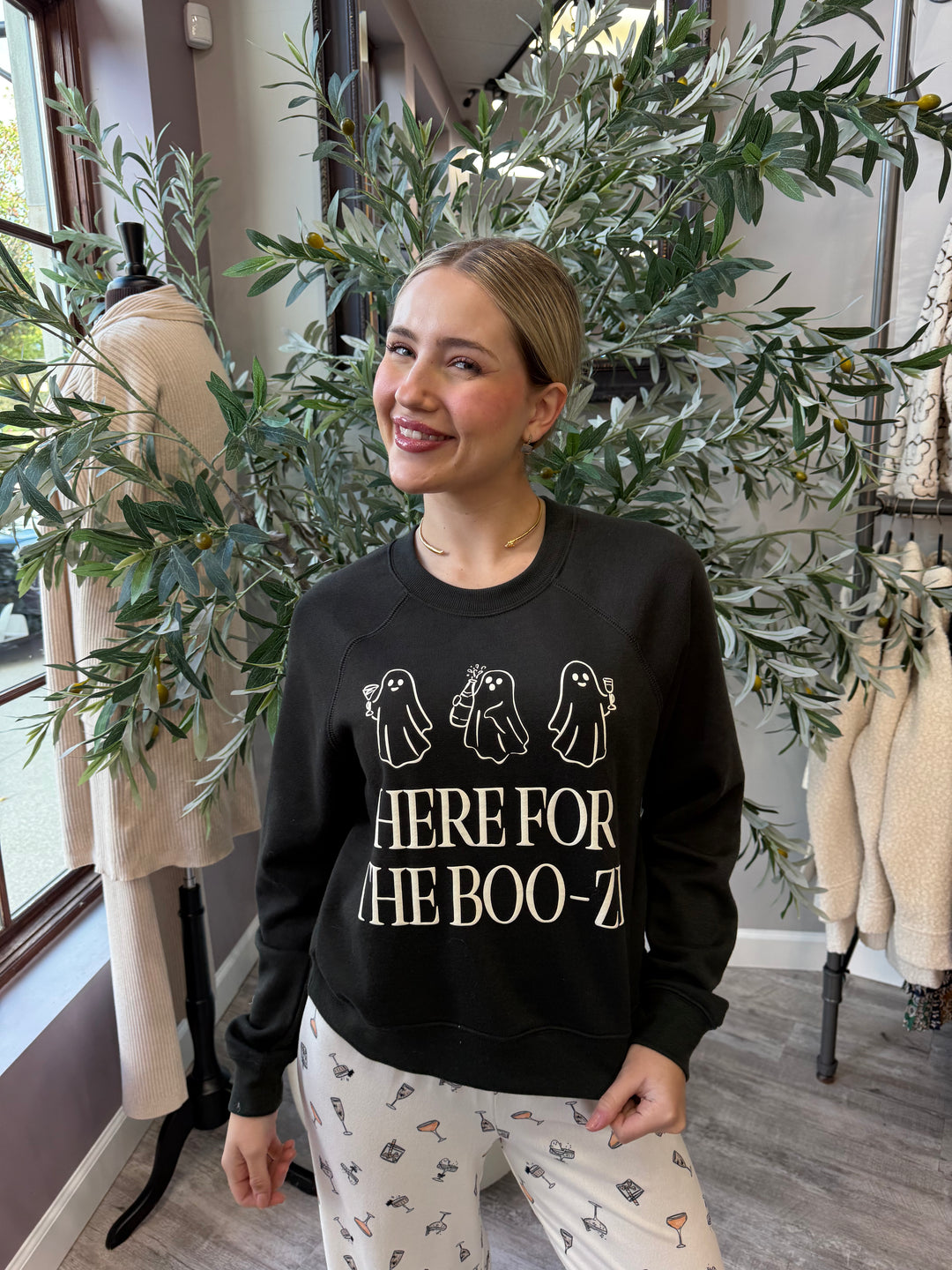 Here for the Boo-ze Sweatshirt in black with cream ghost trio graphic, waist-up front view